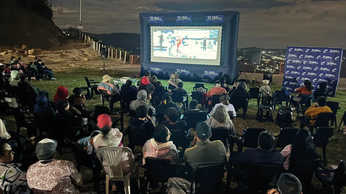 Una vereda ve cine al aire libre en pantalla gigante durante la noche