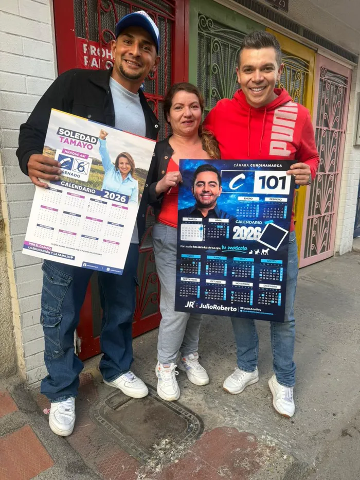 Vecinos sostienen calendarios de la campaña C101 en la puerta de su casa